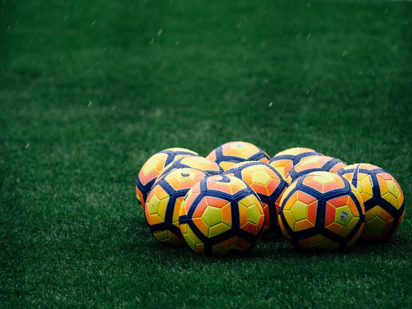 Footballs stacked on a training pitch before a camp