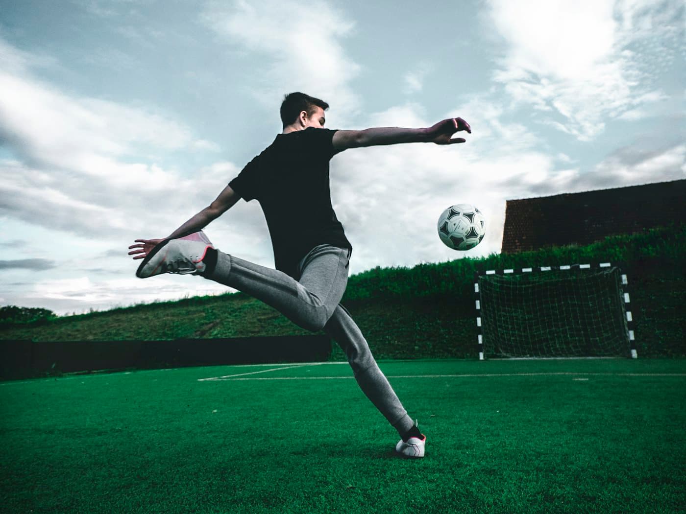A young footballer striking a ball during evening practice